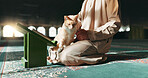 Muslim, person and cat in a mosque during praying, worship or comfort while reading on the floor. Holy, religion and an Islamic man with a pet or animal during spiritual study, learning or relax