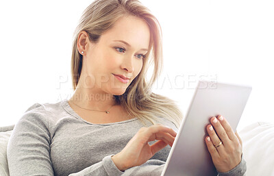 Buy stock photo Shot of an attractive young woman using a tablet at home