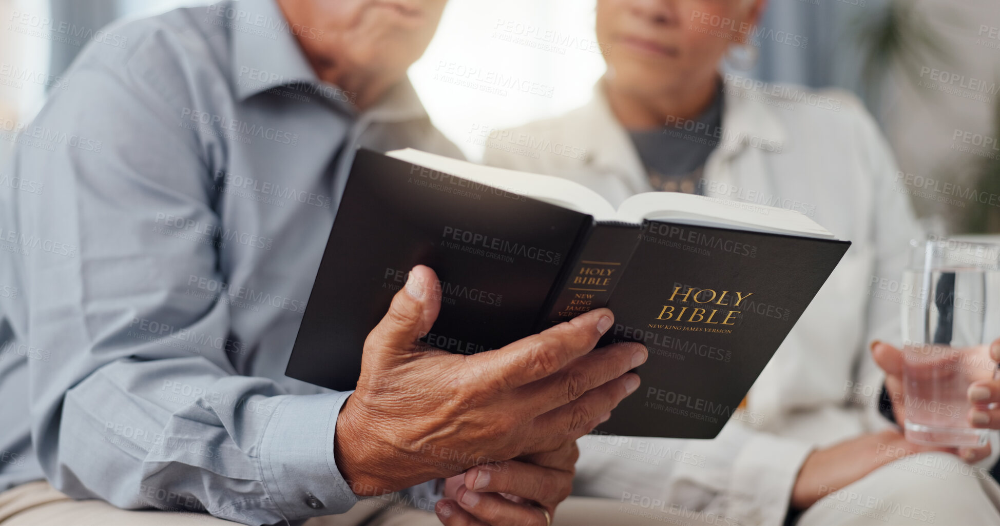 Buy stock photo Couple, hands and home for reading bible, talking of faith and God with helping, support and scripture on sofa. Mature people or pastor in living room with holy book for religion and Christianity