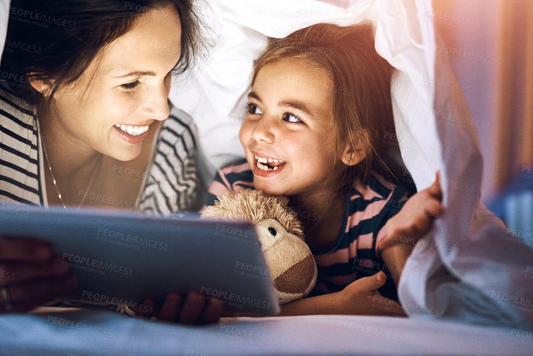 Buy stock photo Cropped shot of an attractive young pregnant woman reading her daughter a bedtime story on a tablet