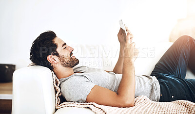 Buy stock photo Shot of a young man using wireless technology on the sofa at home
