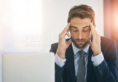 Buy stock photo Shot of a young businessman looking stressed out while working in an office