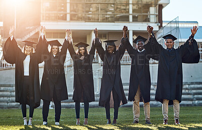 Buy stock photo Portrait of a group of students standing in a line with their arms raised on graduation day