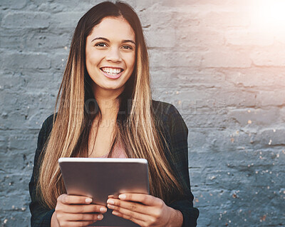 Buy stock photo Portrait of a young woman standing outdoors and using a digital tablet against a gray wall