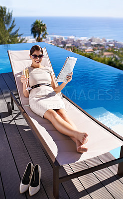 Buy stock photo Woman, happy and magazine on sunbed by pool with sunglasses for relax, article or lifestyle news. Person, champagne and paper outdoor on holiday, vacation or summer trip at hotel or resort with smile