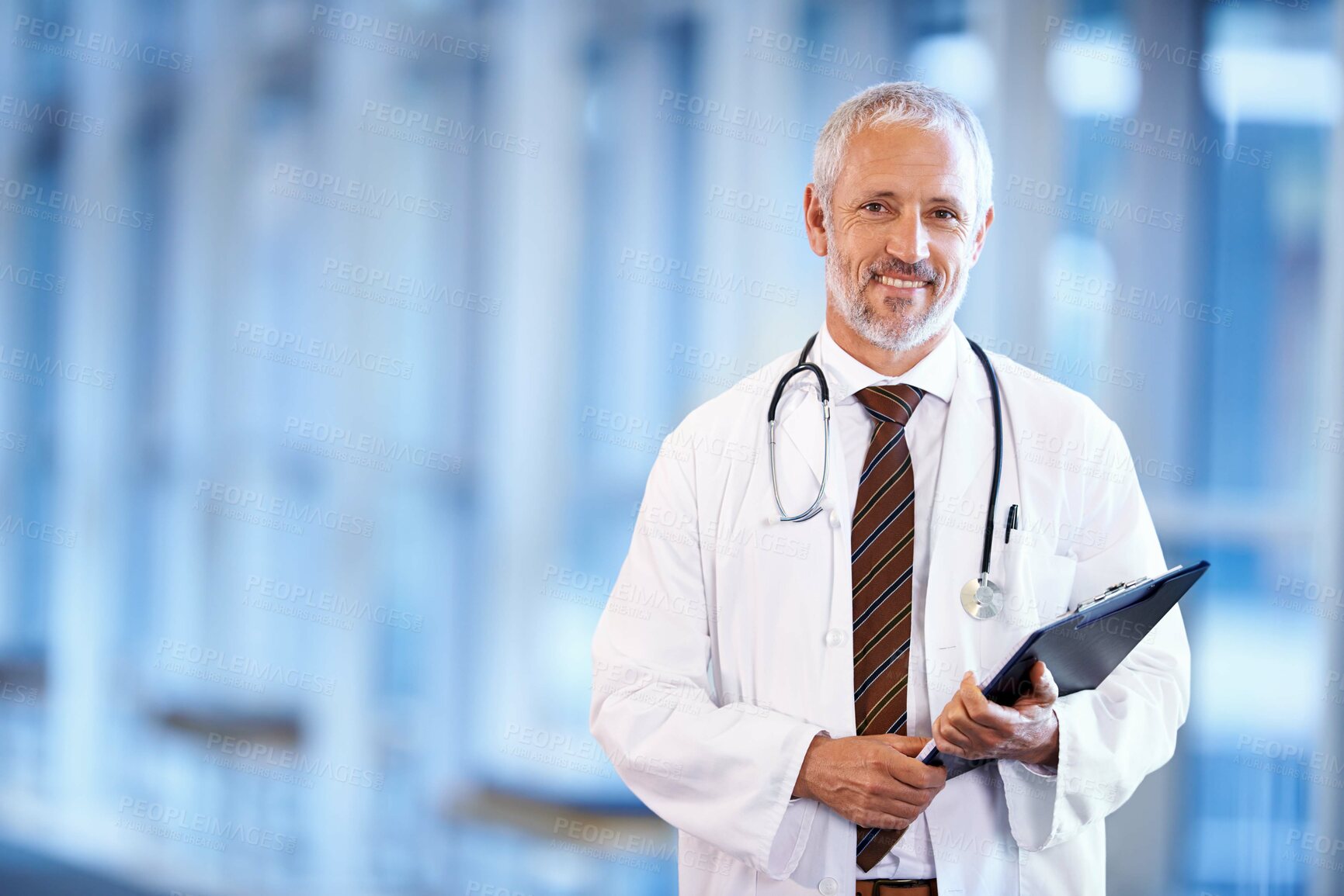 Buy stock photo Portrait of a mature doctor holding a patient file in a hospital corridor