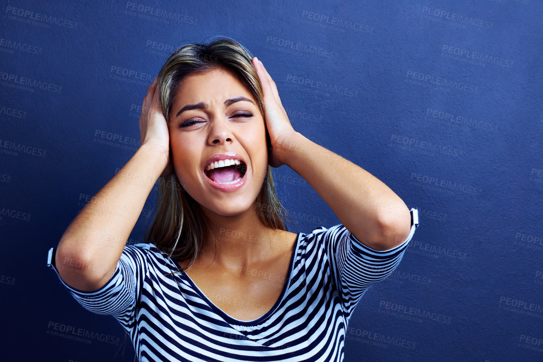 Buy stock photo Woman, noise and cover ears in studio with stress, mental health and shouting with anxiety by blue background. Girl, person and model with tinnitus, frustrated and stop sound with hands on head