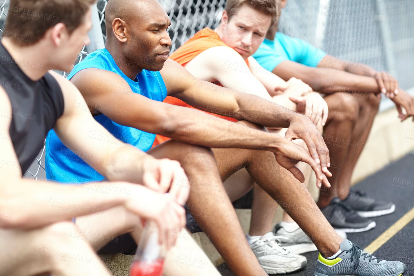 Buy stock photo Cropped side view of male athletes resting on the side of the race track