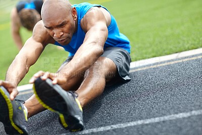Buy stock photo Close up of a male athlete stretching his muscles at the race track