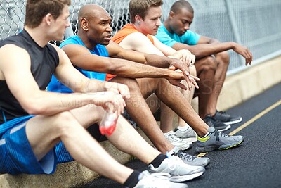 Buy stock photo Side view of male athletes resting on the side of the race track