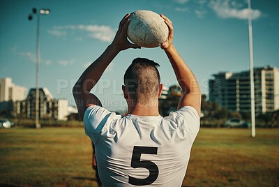 Buy stock photo Rearview shot of an unrecognizable rugby player throwing a ball during a lineout on the field during the day