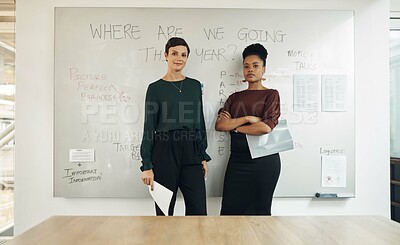 Buy stock photo Cropped portrait of two attractive young businesswomen standing in front of a whiteboard in their office boardroom