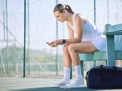 Buy stock photo Female tennis player with a phone checking fitness goal progress on modern exercise app online while taking a break on the court. A sports woman looking at messages on cellphone and waiting for coach