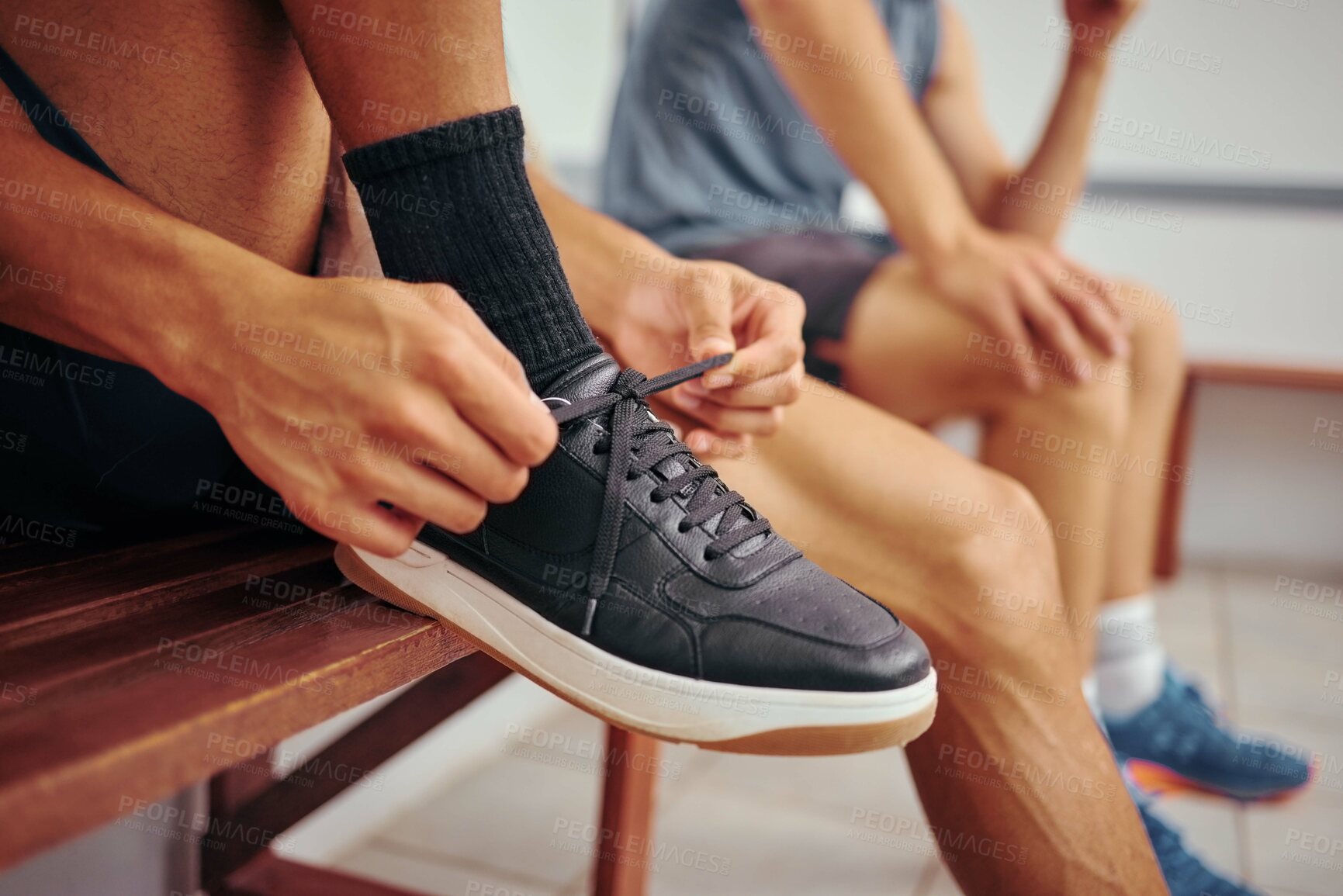 Buy stock photo Squash player tying his shoe lace. Hands of a fit athlete getting ready for a squash match. Closeup of a player tying the laces of his sport sneaker. Player sitting on a bench with his friend.