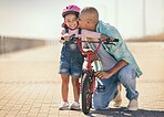 Father, child and kiss while outdoor with a bicycle with a girl learning, development and training on a bike in summer for fun, love and quality time. Man teaching kid to ride at a park on vacation