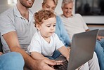 Family, laptop and baby in living room learning how to type or playing game. Big family, education and development of child, infant or kid on computer with father, grandmother and grandfather in home