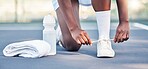 Tennis, athlete and sports feet tying her shoe laces ready for game, competition or training outdoor with water bottle gear. Fitness sneakers of black woman foot on ground zoom in workout motivation