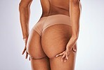 Cellulite, ass and underwear with a model black woman in studio on a gray background for body positivity. Stretch marks, real and natural buttocks with a female posing in lingerie from the back