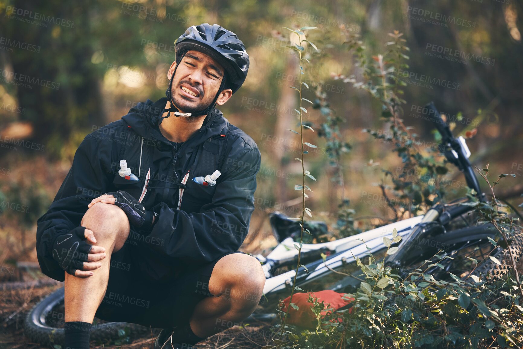 Buy stock photo Forest, cycling and Asian man with knee pain, training and muscle tension in nature, emergency and accident. Male rider, athlete or person with bicycle, leg injury and outdoor for practice and strain