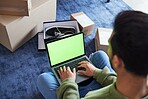 Ecommerce, man with computer, green screen and box on carpet, shoes and delivery service on digital app. Sale, discount and online shopping on fashion retail brand website, internet search on laptop.