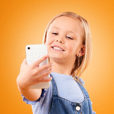 Buy stock photo Phone, selfie or face of child in studio with confidence or mockup space in photograph memory. Kid, orange background or happy girl taking picture online on a social media app to post on internet