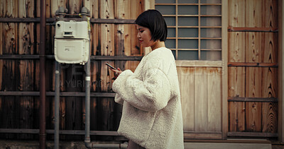 Buy stock photo Japanese woman, phone and texting in street, thinking and reading for communication, notification or app. Girl, person and smartphone with mobile network, social media and walk on metro road in Tokyo