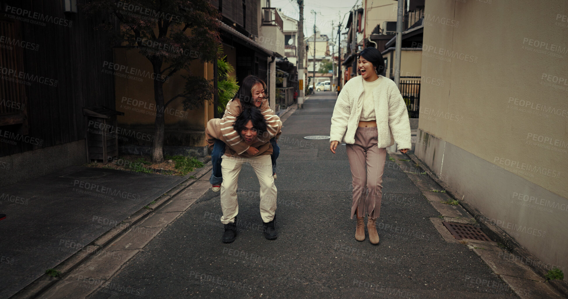 Buy stock photo Women, friends and piggy back in city, talk and travel together on vacation, street and buildings. Japanese people, girl and outdoor in metro road, houses and urban neighborhood with chat in Tokyo