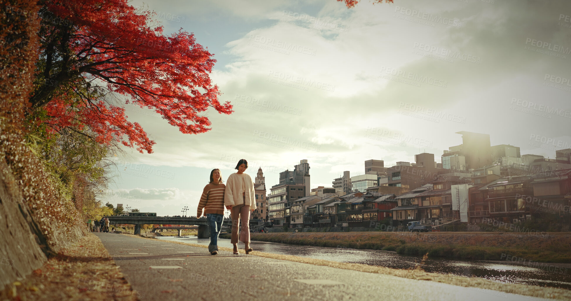 Buy stock photo Japanese woman, walking and canal in city by autumn leaves and happiness for bonding in nature. Friends, smile and together in wellness by red maple tree, care and cloudy sky in tokyo for sunlight