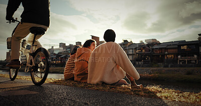 Buy stock photo Friends, sitting and talking in city outdoor with travel, gen z and happy discussion together in japan. People, bonding and back in tokyo town on vacation and holiday with wellness by water canal