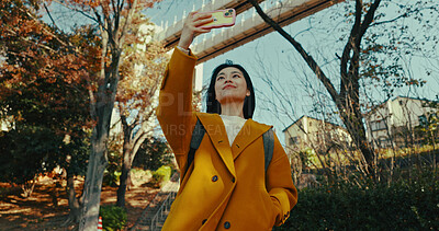 Buy stock photo Japanese woman, selfie and smartphone in city with happiness, holiday adventure and wellness by technology. Person, smile or fashion in tokyo park by outdoor, autumn leaves or urban town with mobile