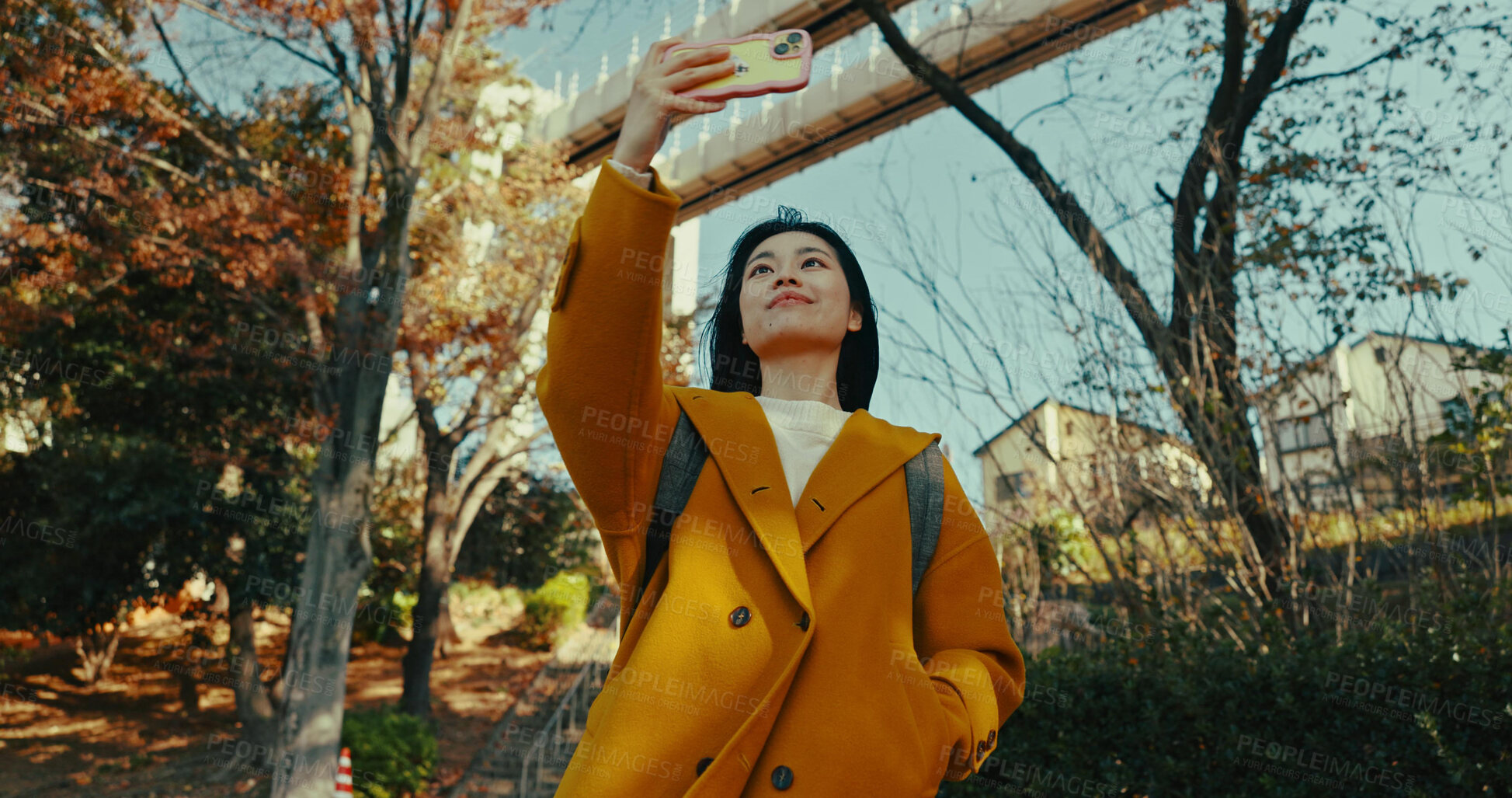 Buy stock photo Japanese woman, selfie and smartphone in city with happiness, holiday adventure and wellness by technology. Person, smile or fashion in tokyo park by outdoor, autumn leaves or urban town with mobile