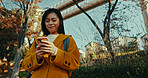 Japanese woman, city and phone for typing on social media, scroll notification and download digital app outdoor. Happy urban commuter with smartphone technology to search for travel location in Tokyo