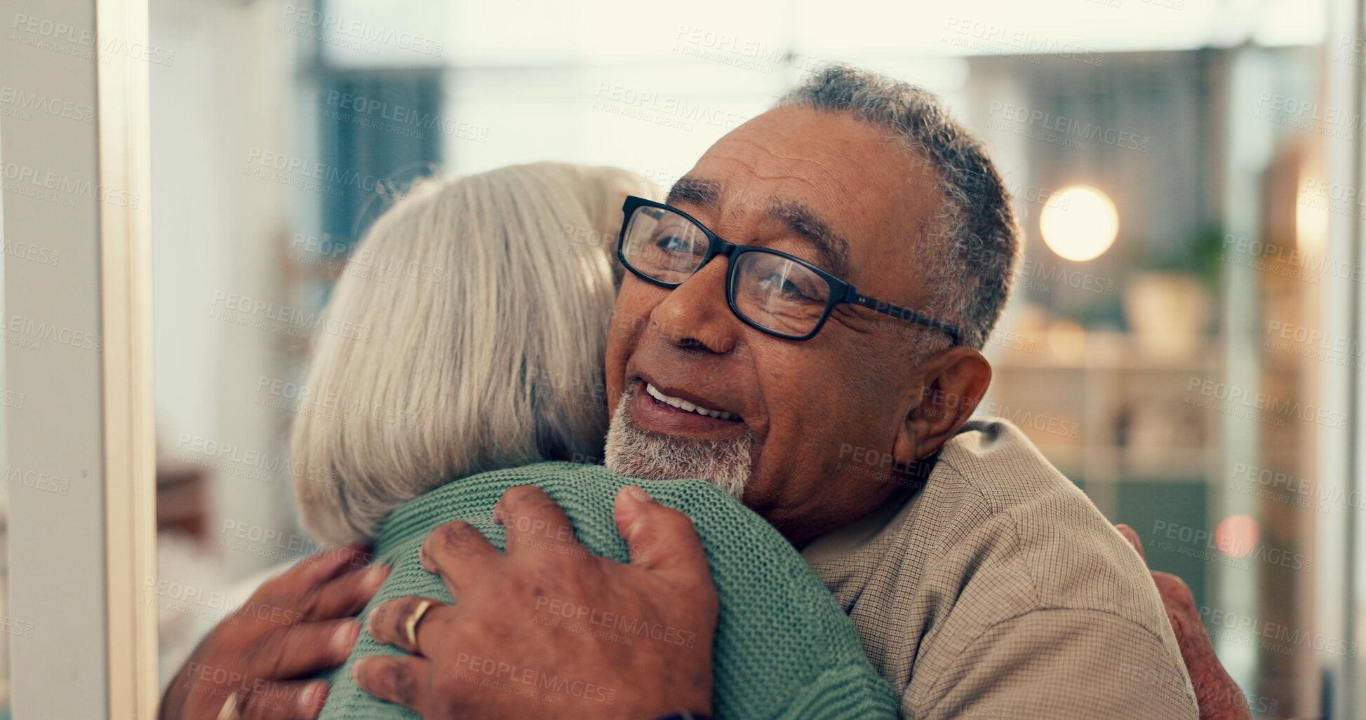 Buy stock photo Love, hug and senior couple in home, together and support, trust or care during retirement. Diversity, smile and happy with elderly man, woman and embracing for romance in their house for wellness