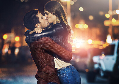 Buy stock photo Shot of a young couple sharing a romantic kiss together outside at night