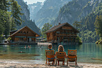 Vacation, lake and family sitting on sand during summer vacation in remote area with cabin, mountains and water background. Holding hands with river or sea view on peaceful holiday in nature