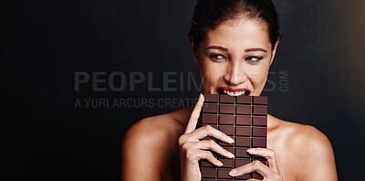 Buy stock photo Studio shot of an attractive young woman biting into a slab of chocolate