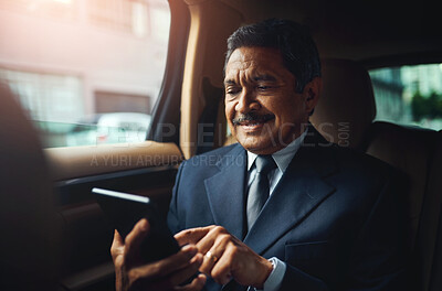 Buy stock photo Shot of a mature businessman using a phone and digital while traveling in a car