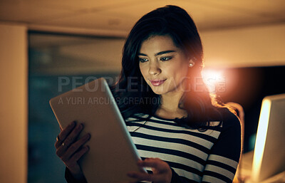 Buy stock photo Shot of a young businesswoman working late on a digital tablet in an office