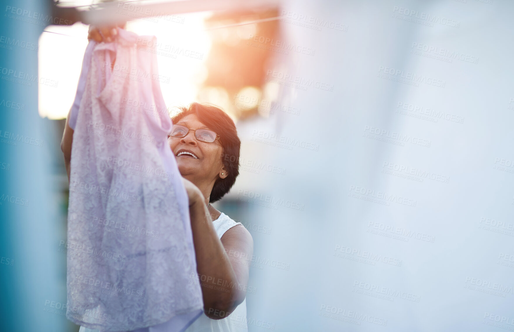 Buy stock photo Shot of a mature woman hanging up laundry on a washing line