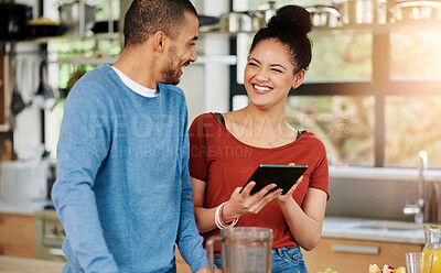 Buy stock photo Shot of a happy young couple using a digital tablet while preparing a healthy snack together at home
