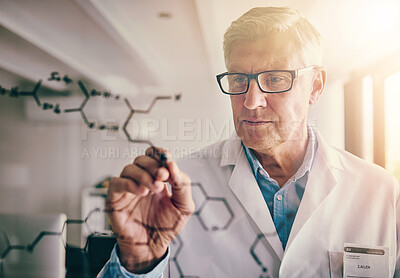 Buy stock photo Shot of a focused mature male scientist solving equations on a glass wall in a laboratory