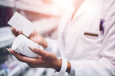 Buy stock photo Shot of a unrecognisable  female pharmacist holding two different types of medication in each hand in a pharmacy