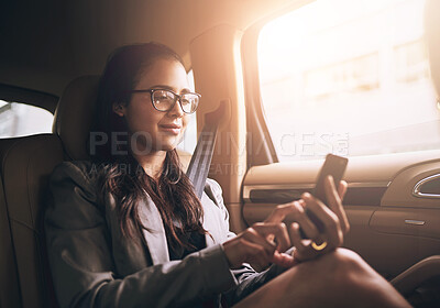 Buy stock photo Shot of a young businesswoman texting on a cellphone in the backseat of a car