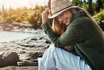 Buy stock photo Woman, smile and relax at lake for travel, forest or outdoor adventure in nature with trees. Female person, happiness and calm by water for vacation in Canada, wellness and peace in park with hat