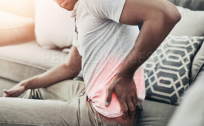 Buy stock photo Shot of a unrecognisable young man holding his lower back in discomfort due to pain in that area
