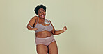 Dancing, body positivity and face of black woman in underwear in a studio for self love celebration. Happy, smile and portrait of young African female model moving with confidence by green background