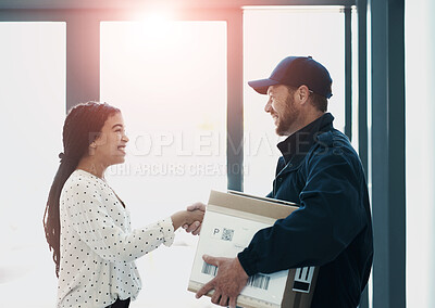 Buy stock photo Shot of a handsome delivery man shaking hands with a female customer