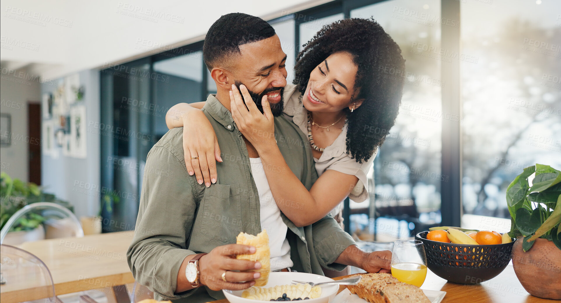 Buy stock photo Happy couple, surprise and breakfast at table with hug, talking and bonding together in morning with love. Man, woman and eating healthy food on kitchen counter, embrace and care in marriage in home