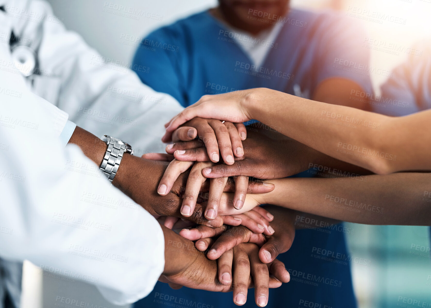 Buy stock photo Shot of a group of unrecognizable doctors forming a huddle with their hands inside of a hospital during the day