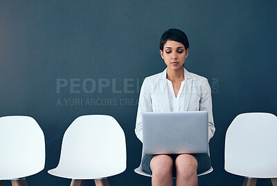 Buy stock photo Studio shot of an attractive corporate businesswoman using a laptop while waiting in line against a gray background